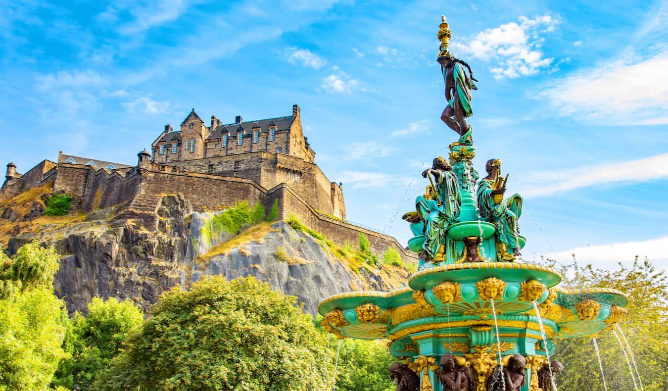 A historic old fountain near the towering Castle in Edinburgh, Scotland on a sunny day