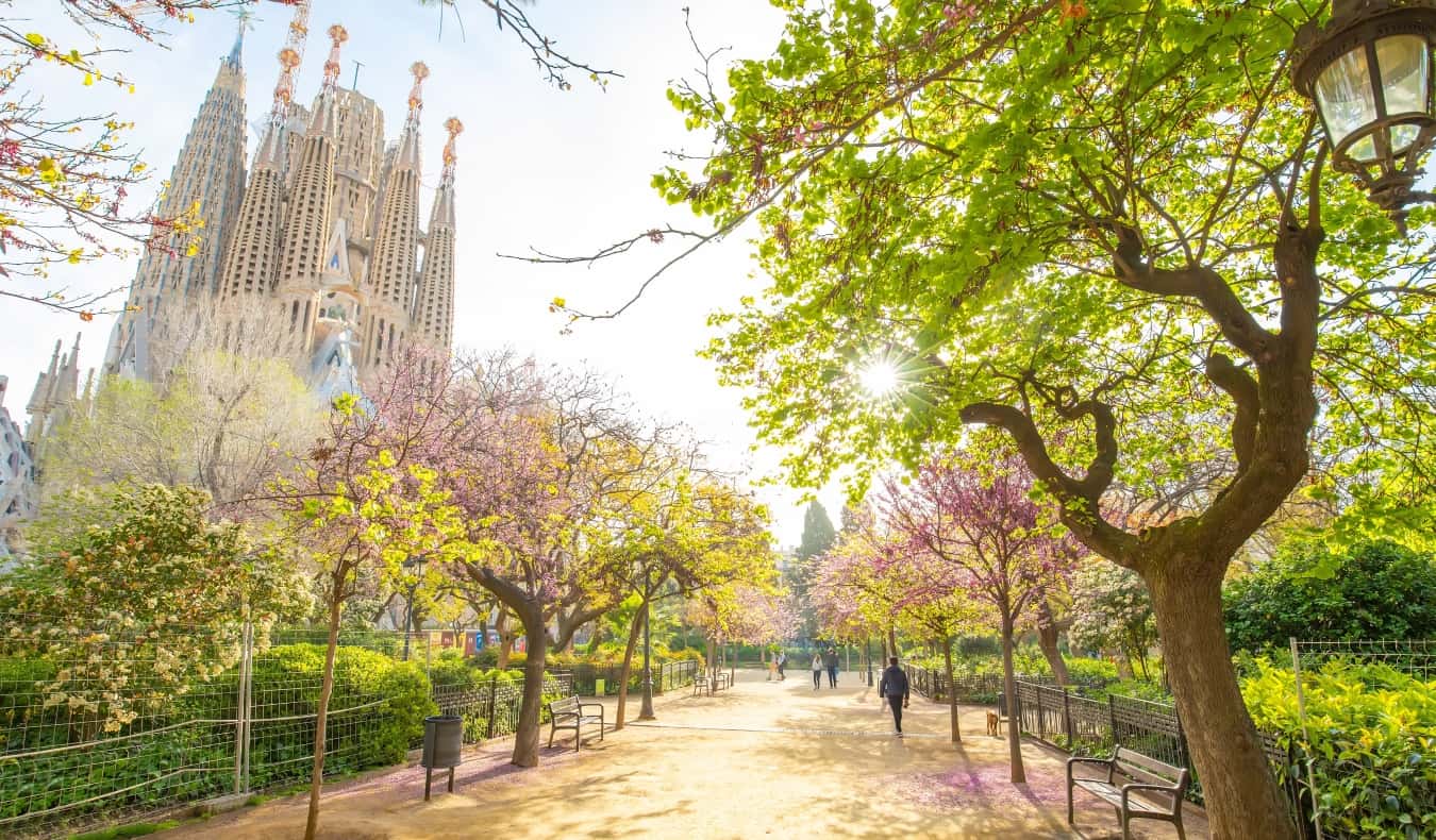 People walking in a park in springtime, with the Sagrada Familia in the background, in Barcelona, Spain